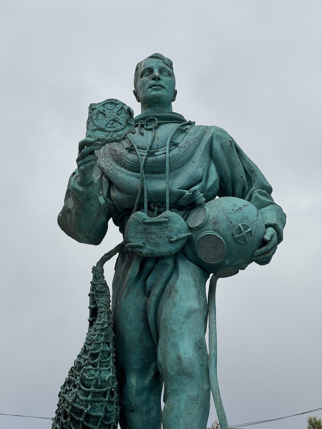 Figure 6 — The statue of a sponge diver on the island of Antikythera, in standard diving dress with his helmet under one arm and the mechanism held up in his other hand: a monument to the divers of 1900–1901,…