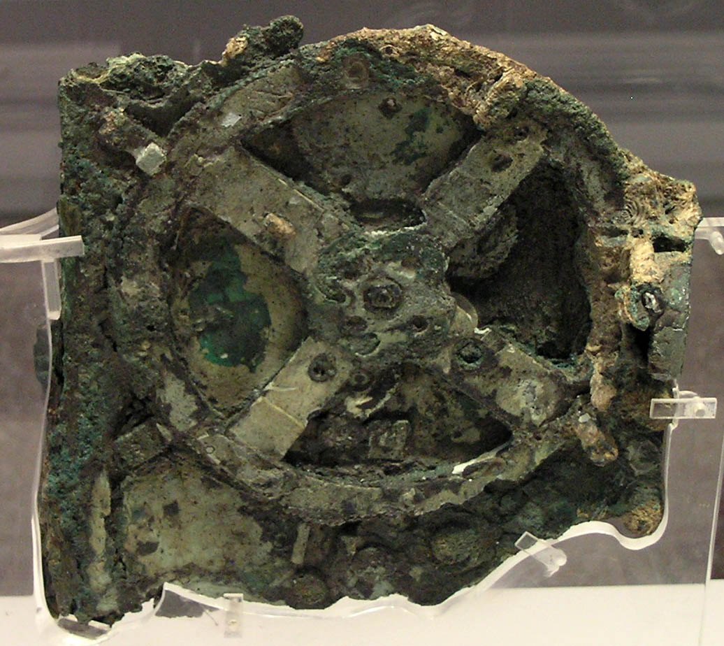 Figure 1 — Fragment A, the largest piece of the mechanism, photographed in its museum case in 2005. The great four-spoked wheel b1 is the feature that every investigator from Stais onwards could see with the …