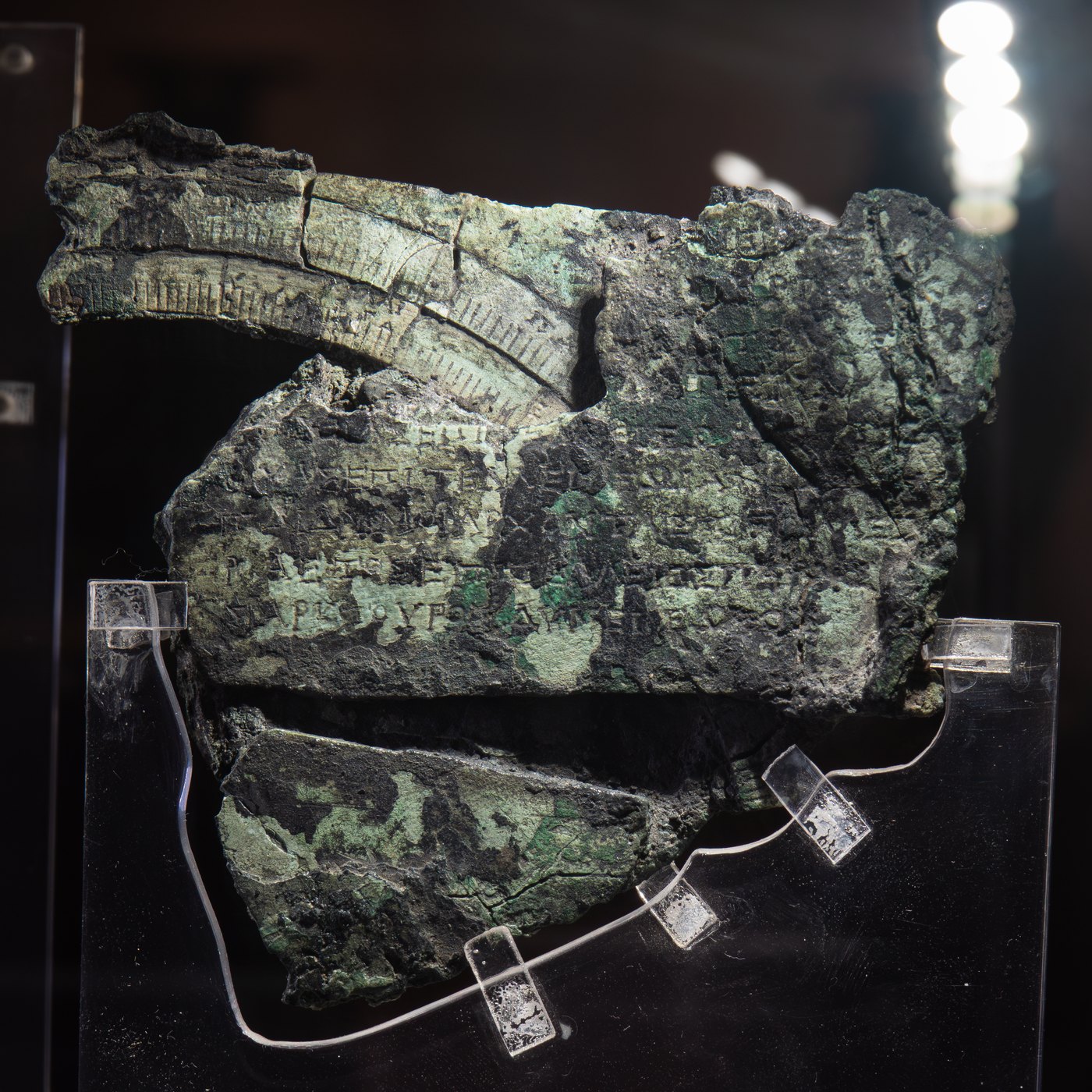 Figure 5 — Fragment C, part of the front dial. The two curved scales are the inner zodiac ring and the outer Egyptian calendar ring, both inscribed in Greek; a gear survives behind them. Price's reading of th…