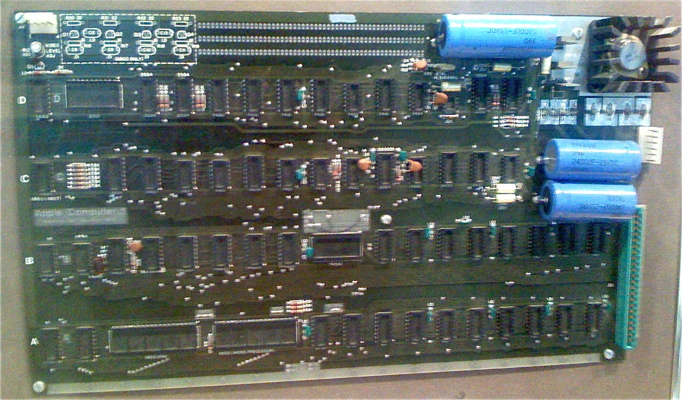 Figure 5 — An early Apple-1 main board, photographed at a vintage-computing display at De Anza College, Cupertino, in 2007. The board is laid out in four rows of chips, labelled A to D at the left edge and 1 …