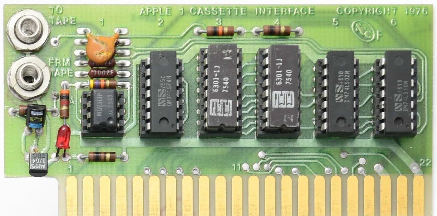 Figure 5 — The Apple Cassette Interface: six chips on a card two inches tall. At left, the TO TAPE and FROM TAPE jacks and the level LED; then the LM311 comparator that squares up the incoming signal; the two…