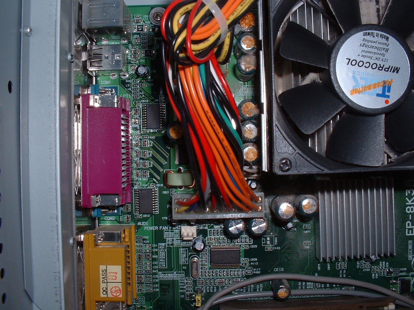 Figure 4 — What failed electrolytic capacitors look like: domed tops and crusted vents, here on a 2000s PC motherboard. An Apple-1's capacitors are older and of a different construction, but the signs to look…