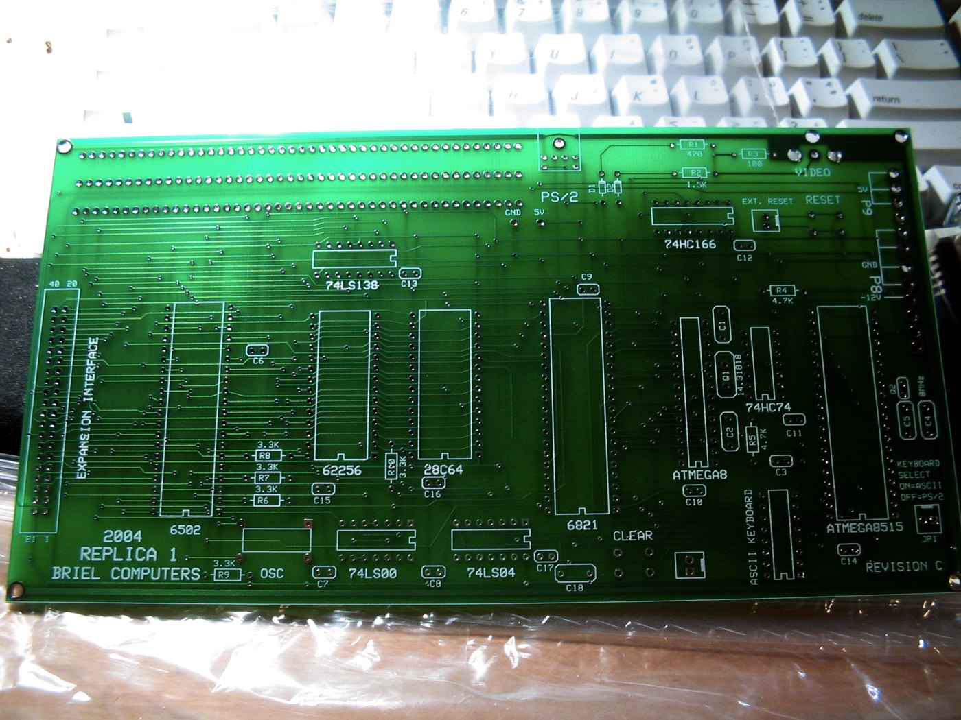 Figure 3 — A bare Replica 1 circuit board of 2004 (revision C), Briel Computers. The silkscreen names the handful of chips that replace the Apple-1's sixty: a 6502, a 6821 PIA, a 62256 static RAM, a 28C64 EEP…