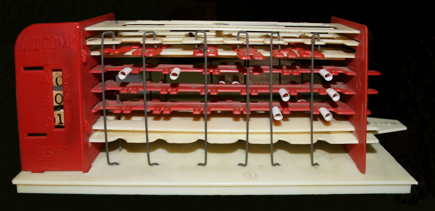 Figure 1 — An original Digi-Comp I of 1963, assembled. The three long red-and-white plates stacked in the frame are the machine's three flip-flops; the vertical wires are its logic rods; the short white tubes…