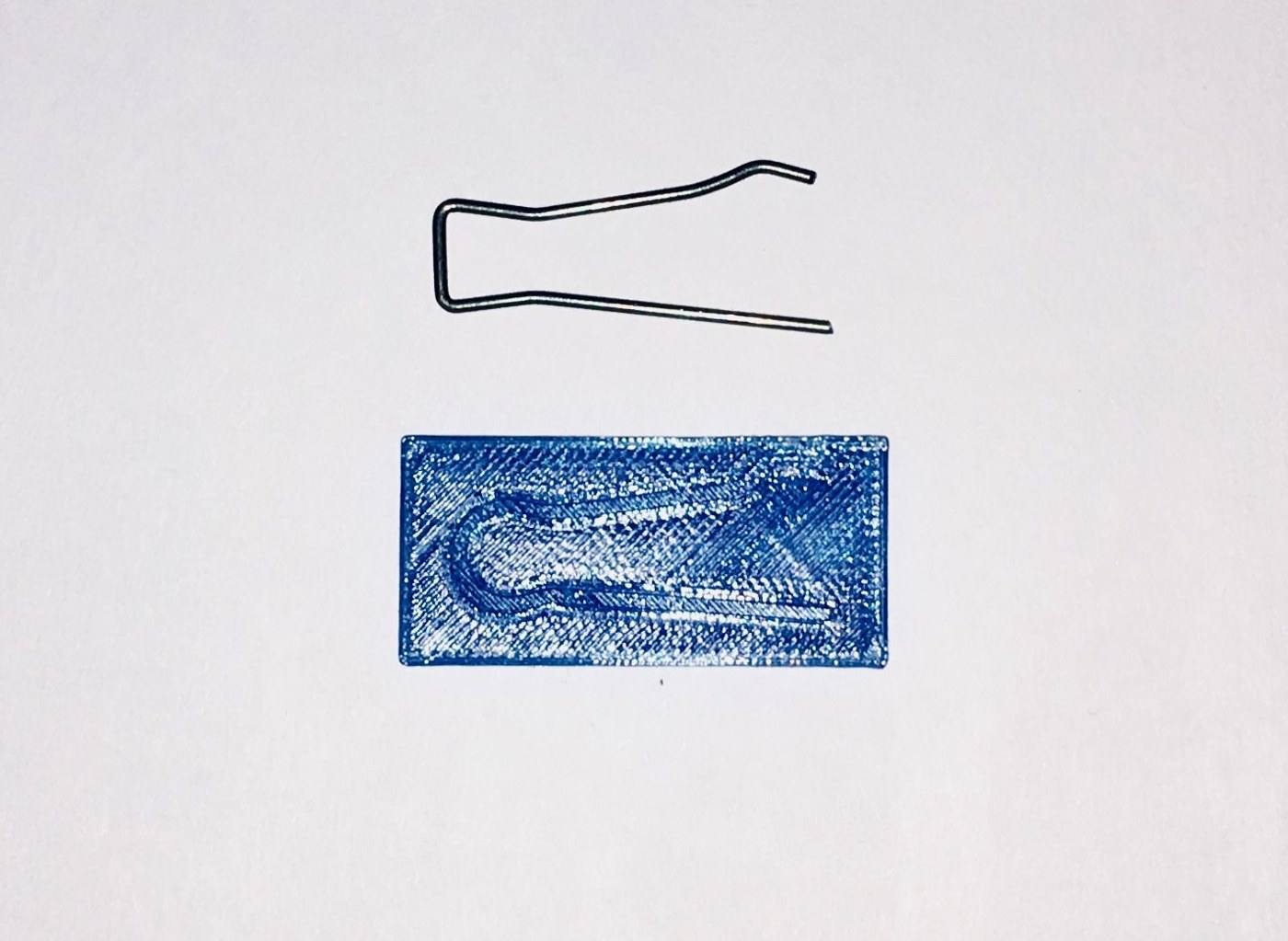 Figure 4 — One of the thirty-three springs that hold each flip-flop and switch to the deck, bent from 1.2 mm piano wire, above the printed template it was bent against. The square top is Gardi's simplificatio…