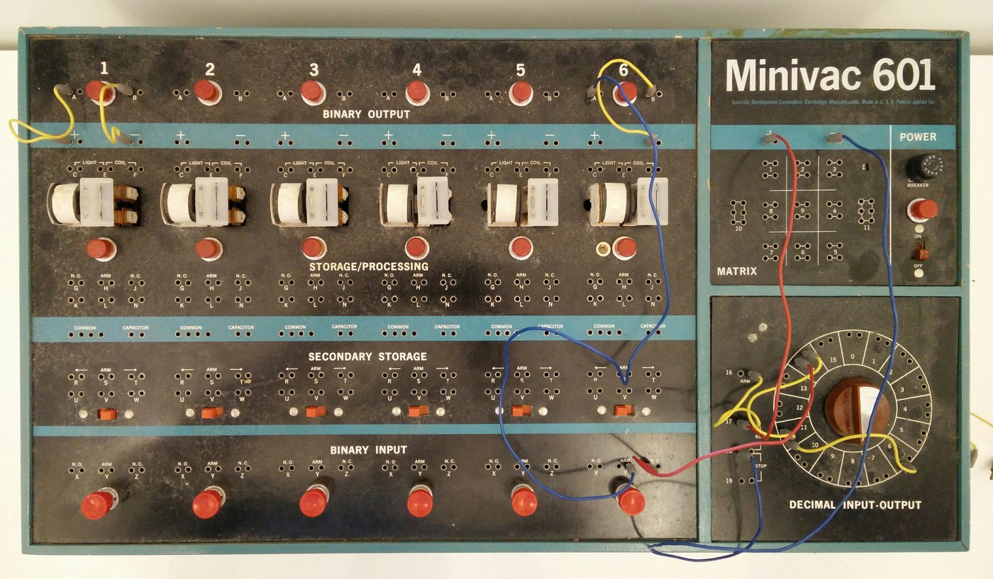 Figure 3 — The Minivac 601 of 1961, designed by Claude Shannon: six relays across the middle of the panel, binary input switches and buttons below, binary output lamps above, and the motorised decimal dial at…