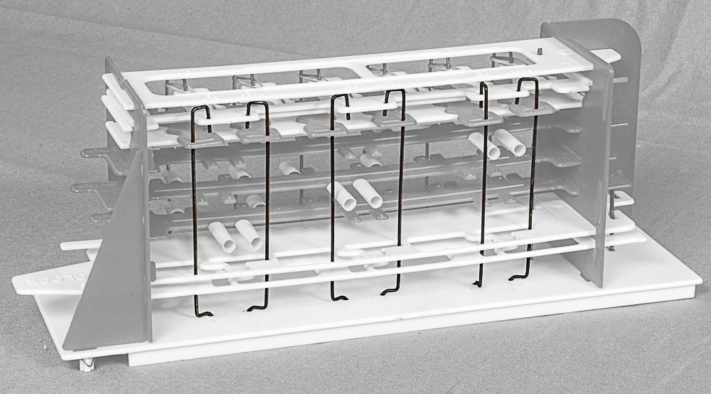 Figure 5 — The back of an original Digi-Comp I with the six clock rods highlighted. Each hangs from the top plate past the numbered back pegs of the three flip-flops; the long clock tubes on those pegs put a …