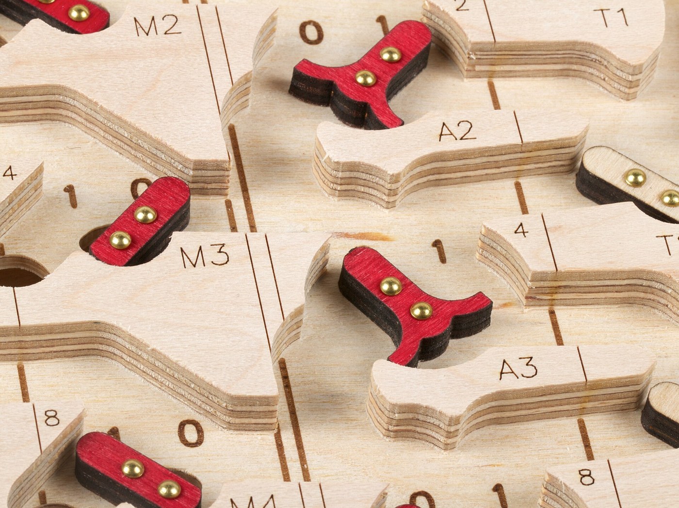Figure 4 — Close-up of the plywood reproduction. The red T-shaped flip-flops are accumulator bits, each with its 0 and 1 marked on the deck beside it; the engraved names A2 and A3 label the channel a marble t…
