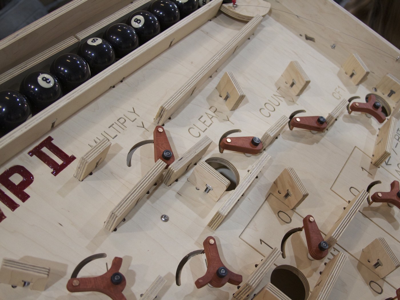Figure 7 — The giant Digi-Comp II close up: the plywood flip-flops of the MULTIPLY, CLEAR and COUNT section, each pivoted on a bolt and printed with its 0 and 1 positions, and the rack of billiard balls along…