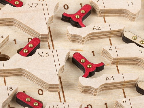 Figure 5 — Detail of the First Edition's playfield: two-layer plywood flip-flops, red on one face and black on the other, pivoted on brass pins over engraved 0 and 1 positions, beside channels routed into the…
