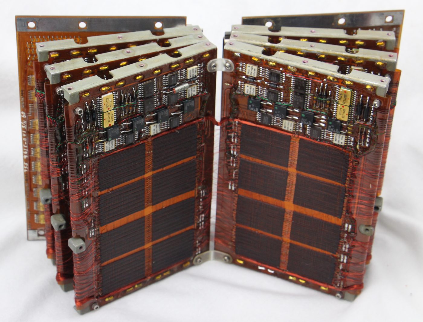 Figure 2 — A magnetic-core memory board of the same era: ferrite rings suspended in a fine grid of wire. Apollo's rope used cores like these but threaded up to 192 sense wires through each one, enc…