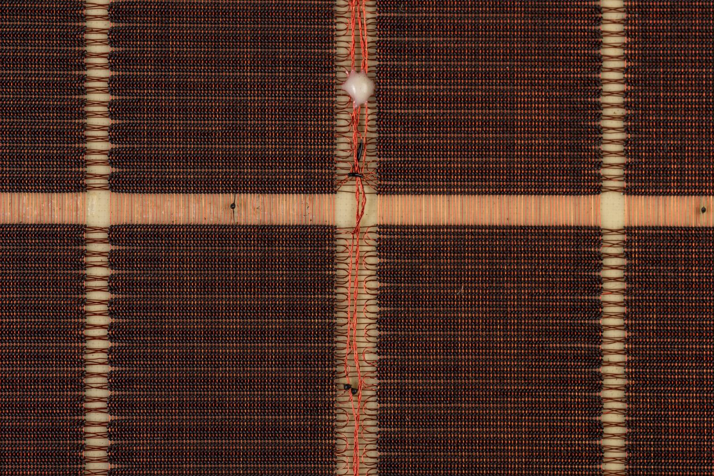 Figure 2 — A close-up of a magnetic-core memory plane: ferrite rings suspended in a grid of fine wire. Apollo's rope used the same cores but threaded far more wires through each one. Photo: File:Mu…