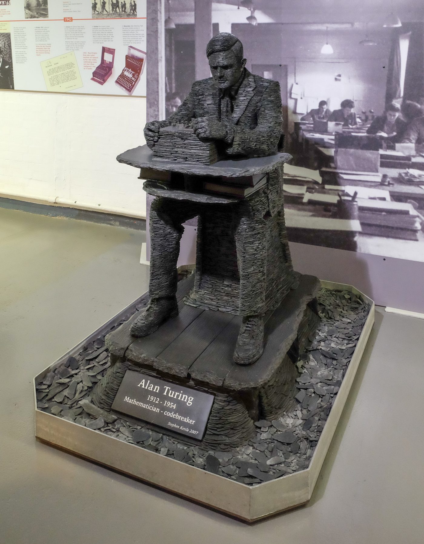Figure 5 — A slate statue of Alan Turing by sculptor Stephen Kettle, on display at Bletchley Park. Turing's wartime work was decisive, but it sat inside a vast collective effort he neither led admi…