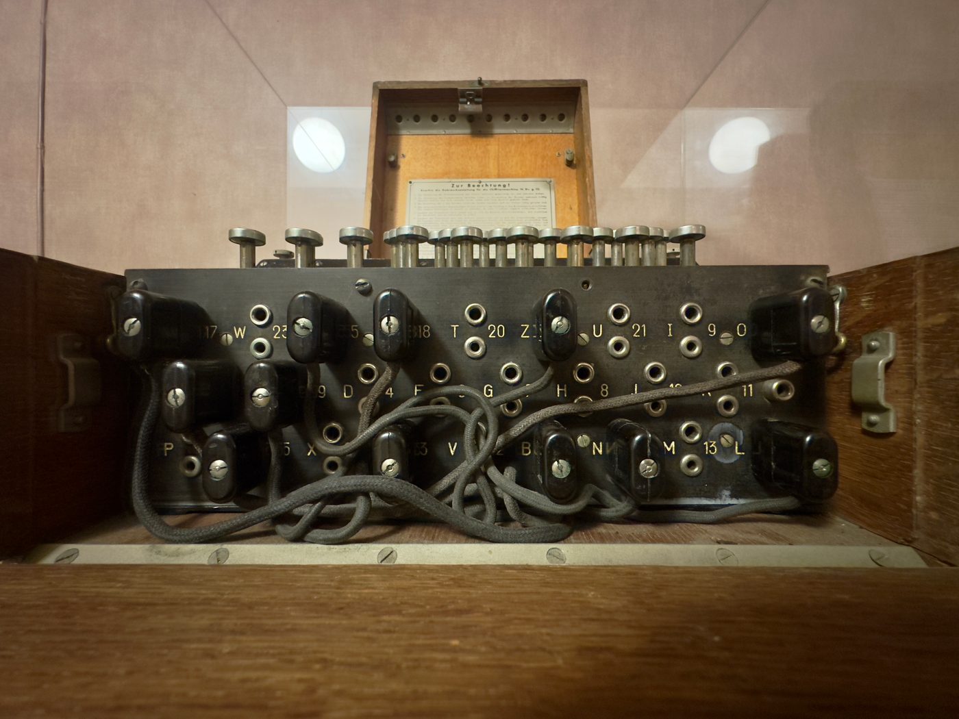 Figure 5 — A military Enigma I (here a 1936 machine on museum display) with the plugboard at the front: the panel of sockets and patch cables, added around 1930, that swapped letter pairs and multi…