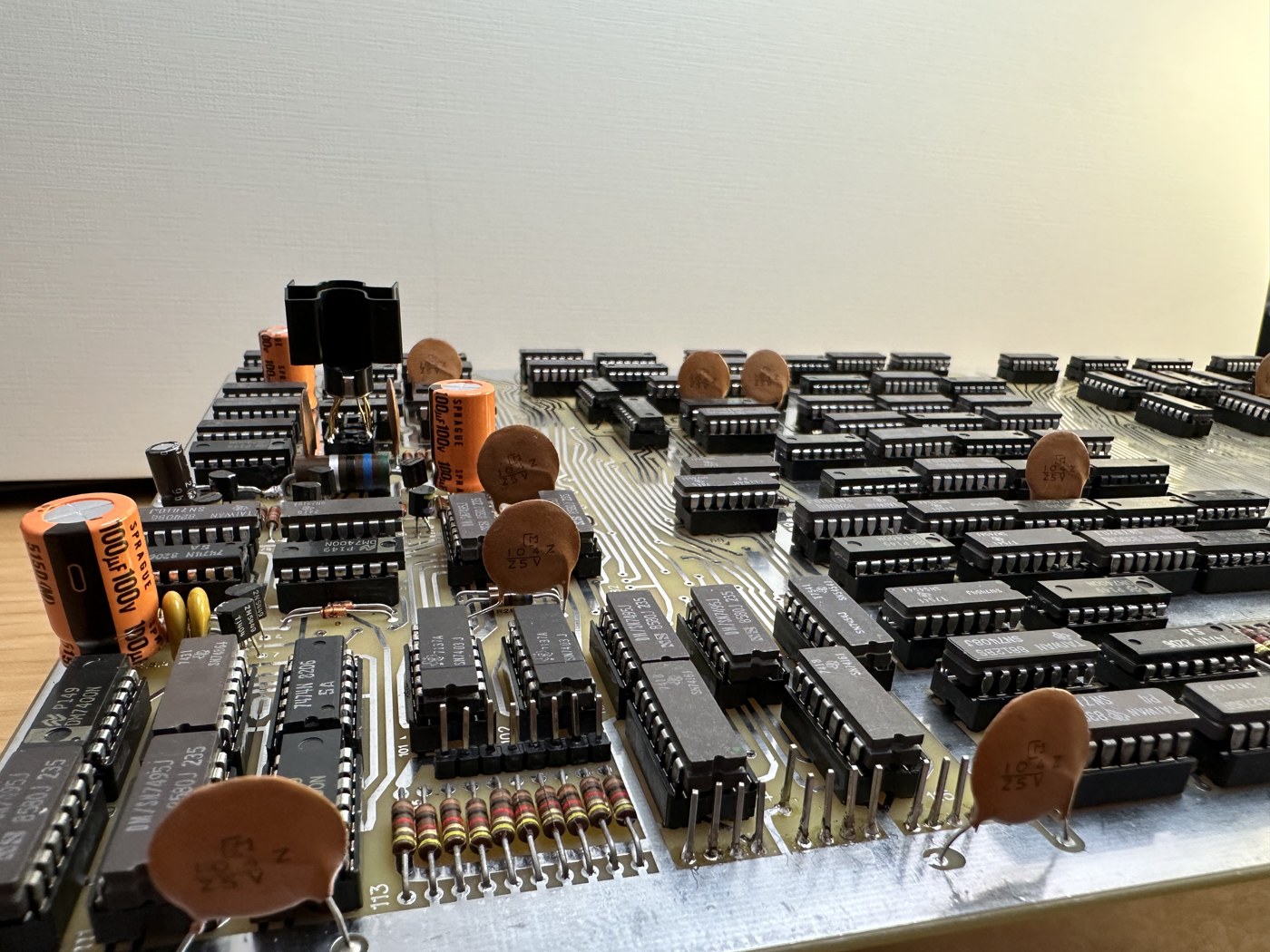 Figure 5 — A reproduction KENBAK-1 board populated with parts from the kit, photographed for the kit listing: rows of 14- and 16-pin TTL packages in sockets, disc and electrolytic capacitors, and the dense tw…