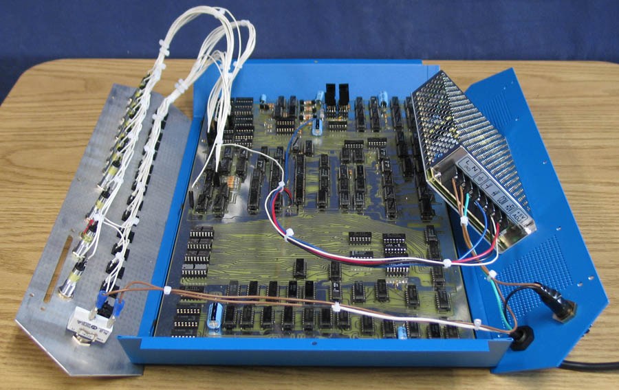 Figure 3 — A KENBAK-1 Series 2 reproduction opened up, 2007: the reproduction Revision B board in the floor of the case, the front panel hinged forward with its wiring loom, and the modern switching power sup…