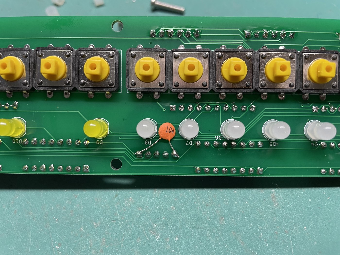 Figure 6 — The front of a µKENBAK-1 board: tactile switches in a row, with the white data LEDs and yellow control LEDs below them. Every switch must be centred on its hole in the panel, or its key cap will bind.