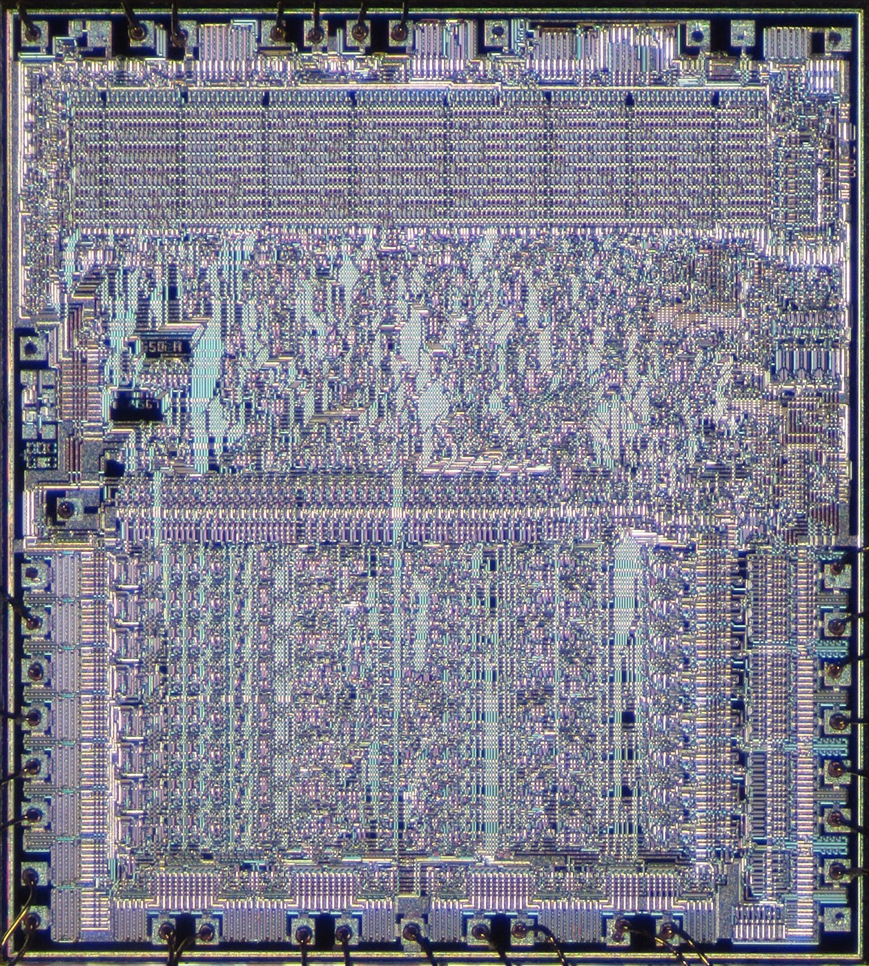 Figure 4 — The 6502 die. The regular block across the top is the instruction decoder, a programmable logic array; the registers and arithmetic unit form the band across the lower half; bonding pads ring the e…