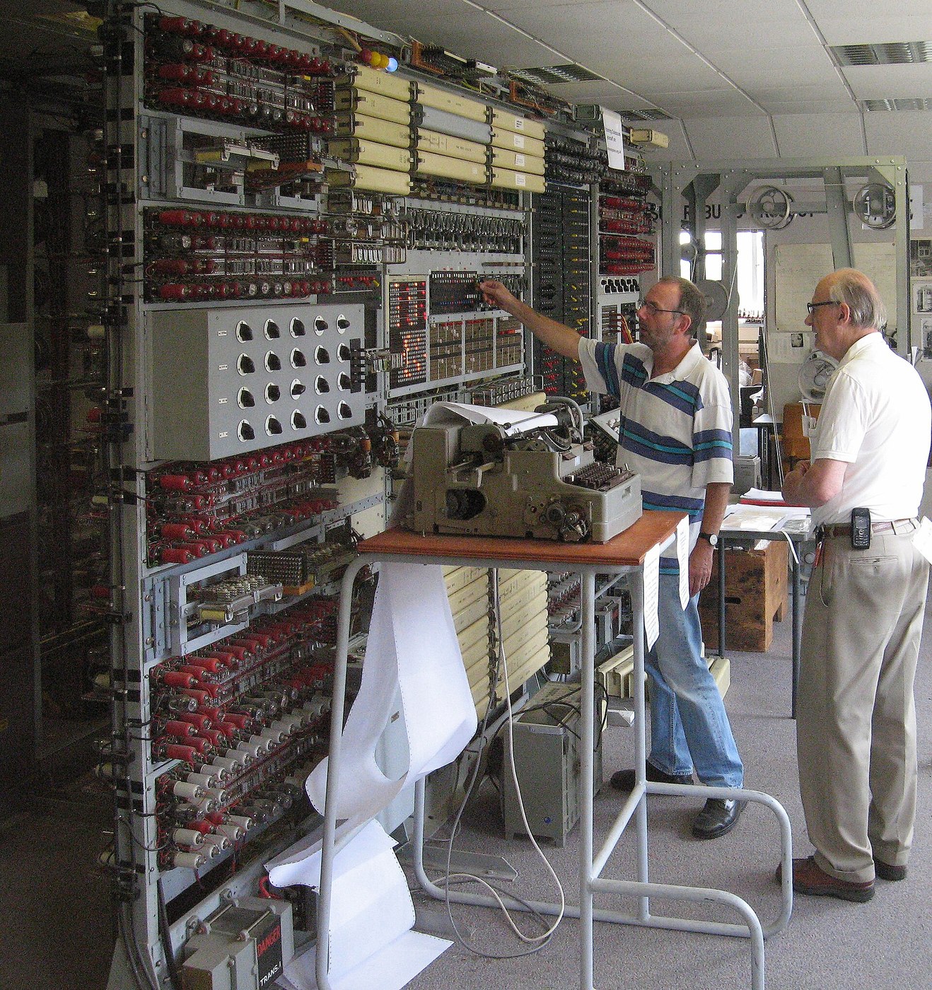 Figure 4 — Tony Sale, who led the reconstruction of Colossus, supervising the breaking of an enciphered message on the completed rebuild at Bletchley Park in 2006. The cipher text runs as a loop of paper tape…