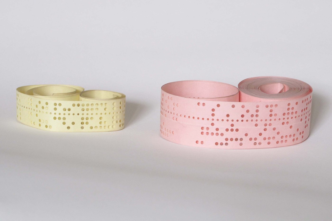 Figure 8 — Five-hole (left) and eight-hole perforated paper tape. Each row of holes across the tape is one character; the smaller holes are the sprocket holes that drive the tape. The Lorenz traffic, its Brit…