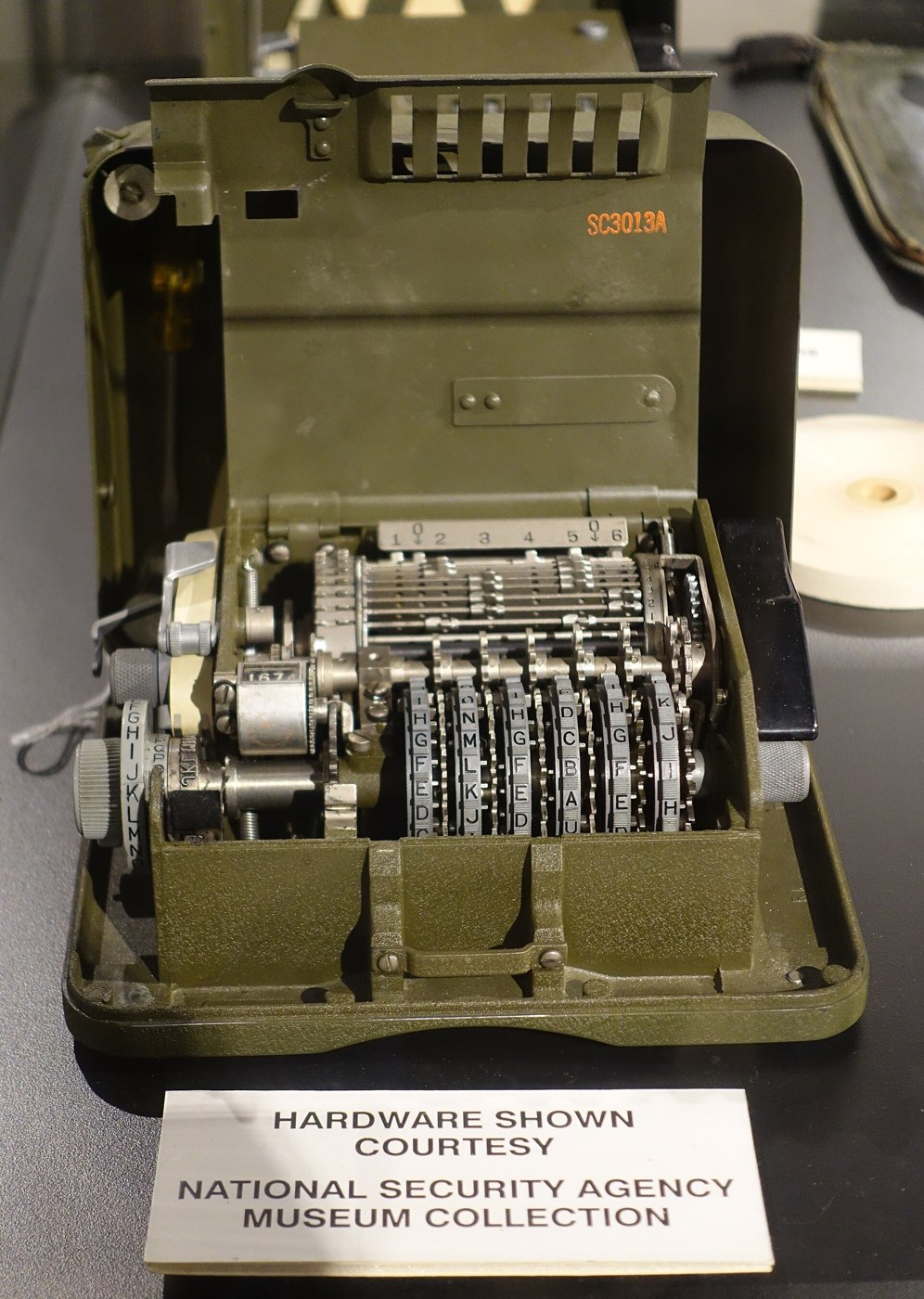 Figure 4 — An M-209 with its inner lid raised, at the National Electronics Museum, Linthicum, Maryland (hardware lent by the NSA's museum). The six key wheels with their rows of pins are at the front; the bar…