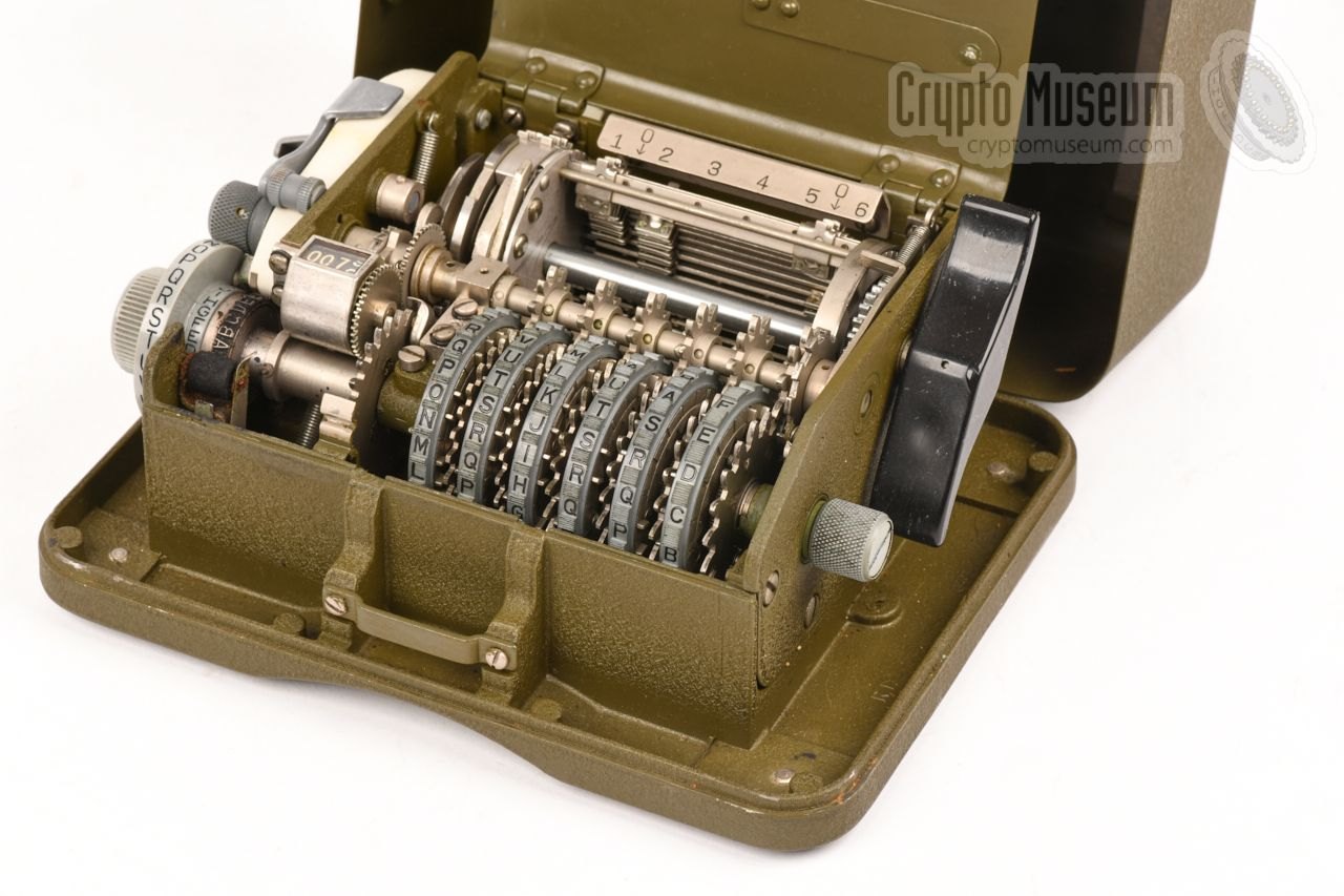 Figure 1 — An M-209 with its lid open: the six pinwheels (front), the drum or "cage" of 27 lug bars behind them, and the print wheel at the left. The pin settings and lug positions inside the case were the "i…