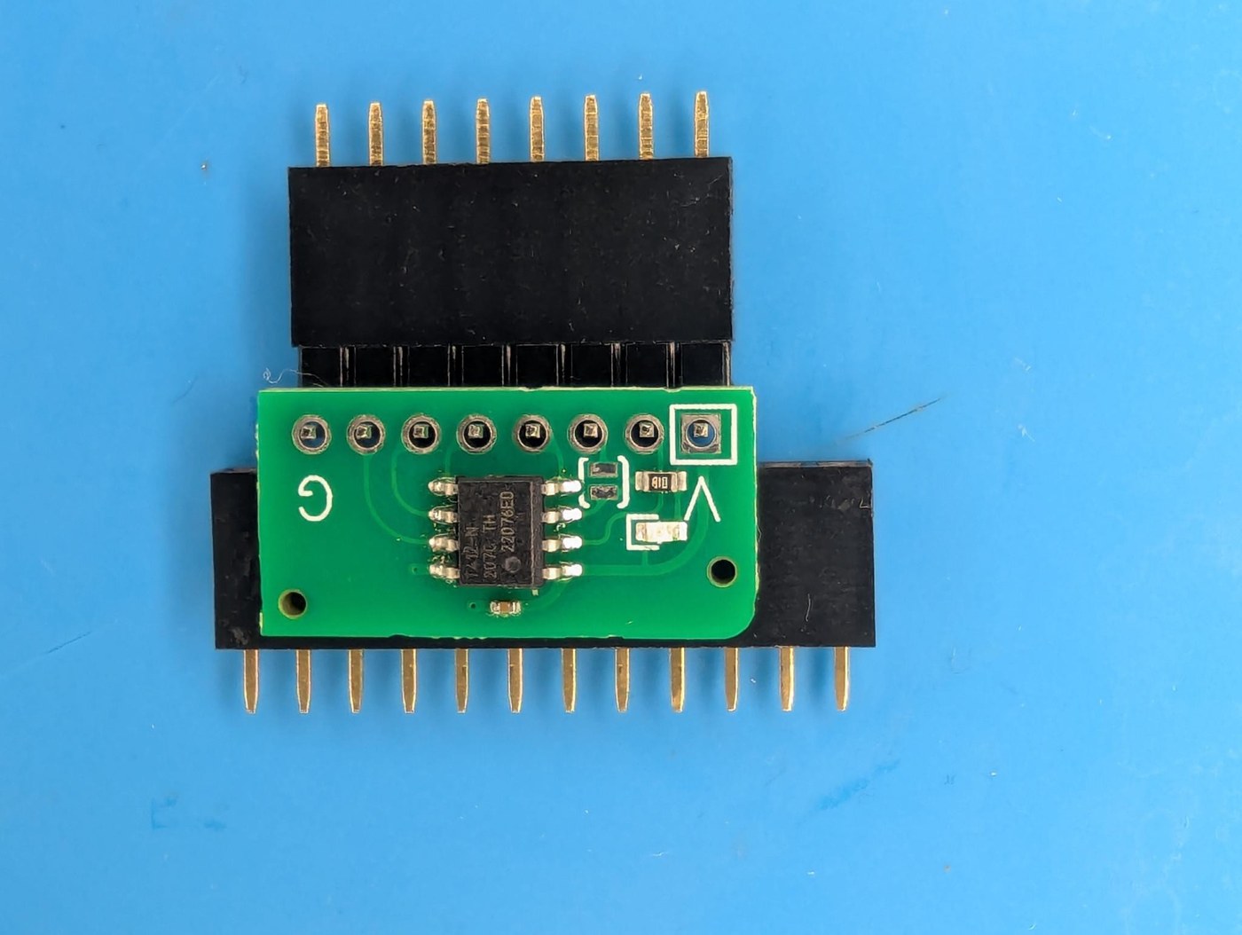 Figure 9 — Soldering the right-angle header square to a card: the card rests on a sacrificial female header, and the header pins are held in a second one so the card stays in the pins' plane.