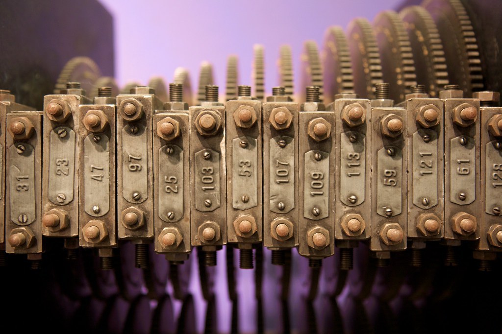 Figure 6 — The upper bank of bearing blocks on the surviving gear sieve, each with an engraved label. Left to right: 101, 31, 23, 47, 97, 25, 103, 53, 107, 109, 113, 59, 121, 61, 128. The labels for the small…