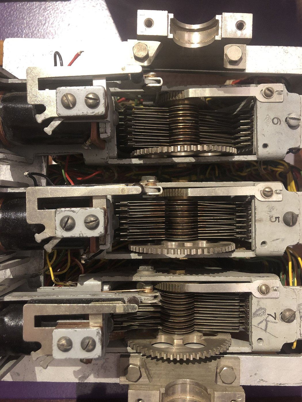 Figure 5 — Looking down into the Berlin fragment: three stepping switches side by side, each with its stack of contact levels, wiper assembly and stepping ratchet. Hand-written figures on the switch frames ap…