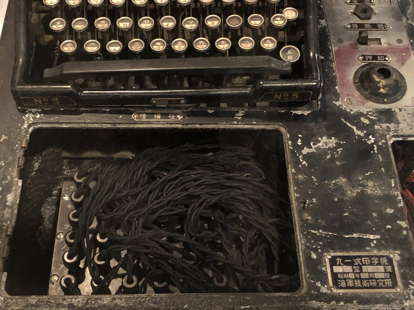 Figure 4 — The plugboard well of the museum's Type 91, with the typewriter keyboard behind. The maker's plate at lower right reads 九一式印字機 ("Type 91 printing machine") and names the Navy Technical Research Ins…
