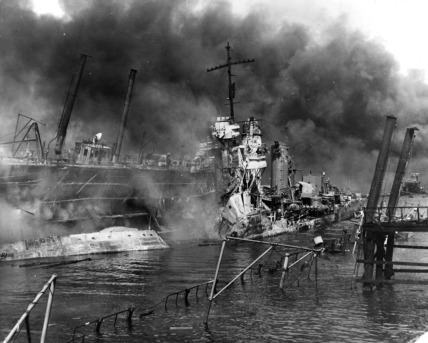 Figure 5 — The destroyer USS Shaw wrecked in the floating drydock YFD-2 at Pearl Harbor on 7 December 1941, after her forward magazines exploded; the listing battleship California is in the distance. The atta…