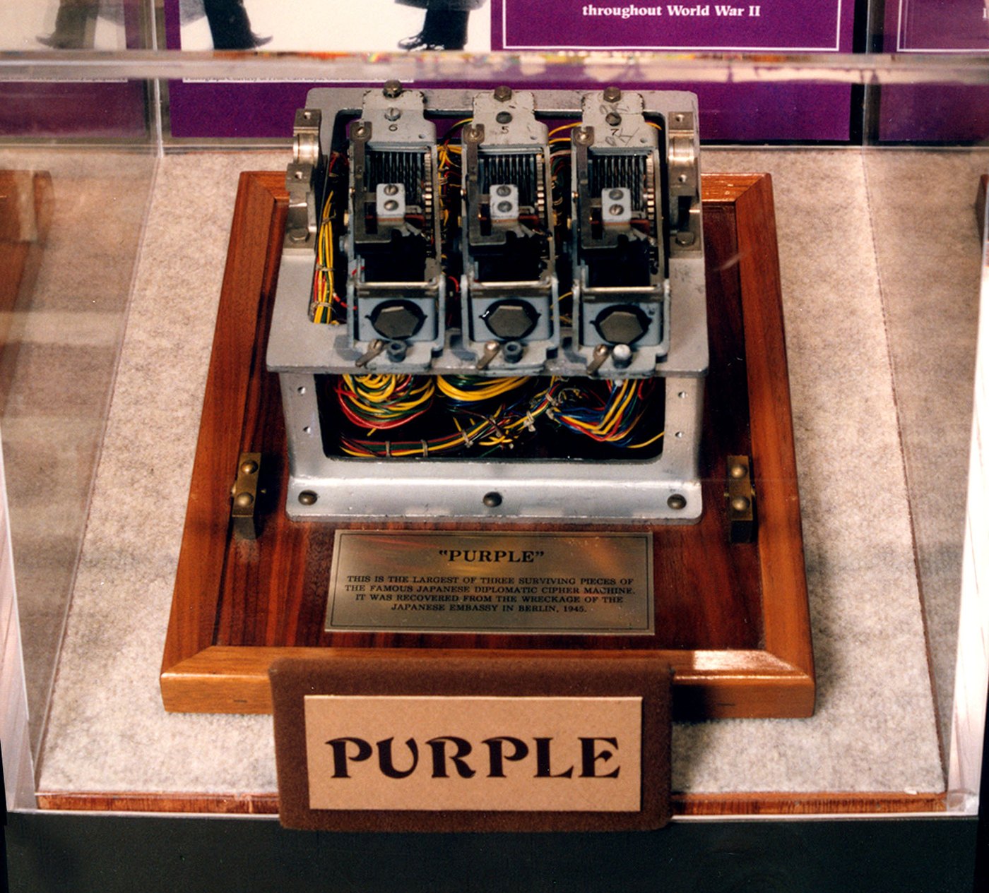 Figure 1 — The Berlin fragment in its case at the National Cryptologic Museum: three stepping switches on a cast frame, with the wiring harness beneath, mounted on a wooden plinth. The plaque reads: "'Purple.…